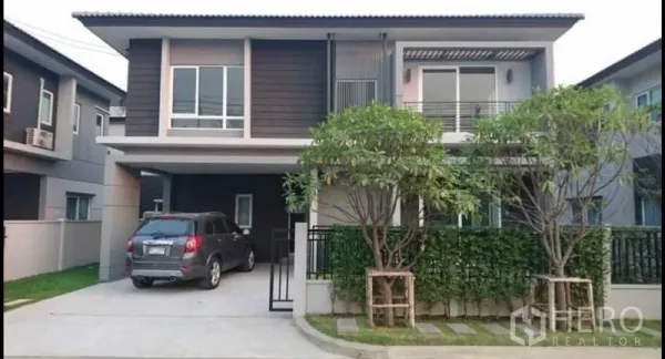 บ้าน ขายในBang Yai, Nonthaburi - บ้านเดี่ยวสองชั้นสมัยใหม่พร้อมที่จอดรถในร่ม ระเบียง และต้นไม้หน้าบ้าน