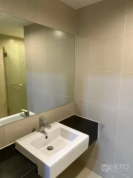 Condominium for rent - Modern bathroom vanity with square sink, wide mirror, and beige wall tiles.