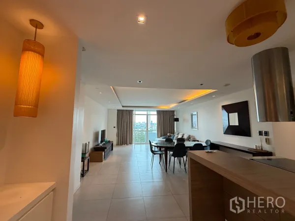 คอนโด ให้เช่าในPhaya Thai, Bangkok - มุมมองจากครัวไปยังโต๊ะอาหารและระเบียง พร้อมไฟฝ้าสีอบอุ่นและวิวเมือง