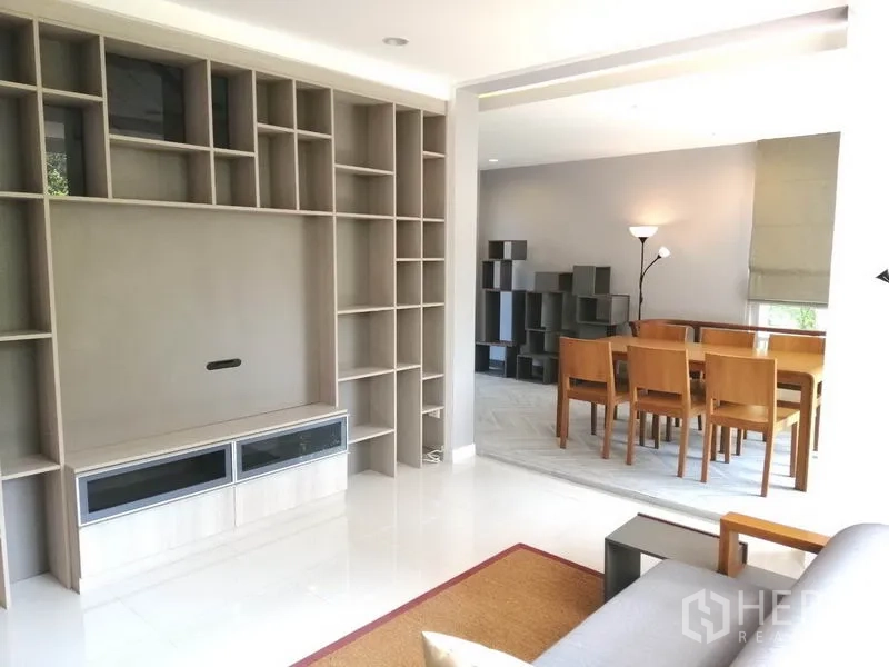 Townhouse for rent or sale in Suan Luang, Bangkok - Bright living room with large built-in wall shelving facing the dining area.