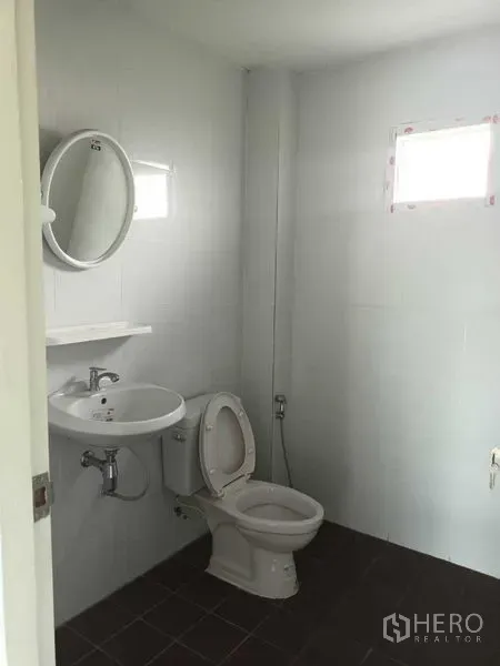 Shophouse for sale in Bueng Kum, Bangkok - Clean bathroom with white tiles, toilet, round mirror and a small window.