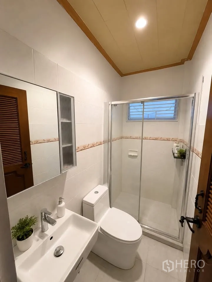 Detached House for rent in Prawet, Bangkok - Clean bathroom with glass-enclosed shower, vanity and toilet.