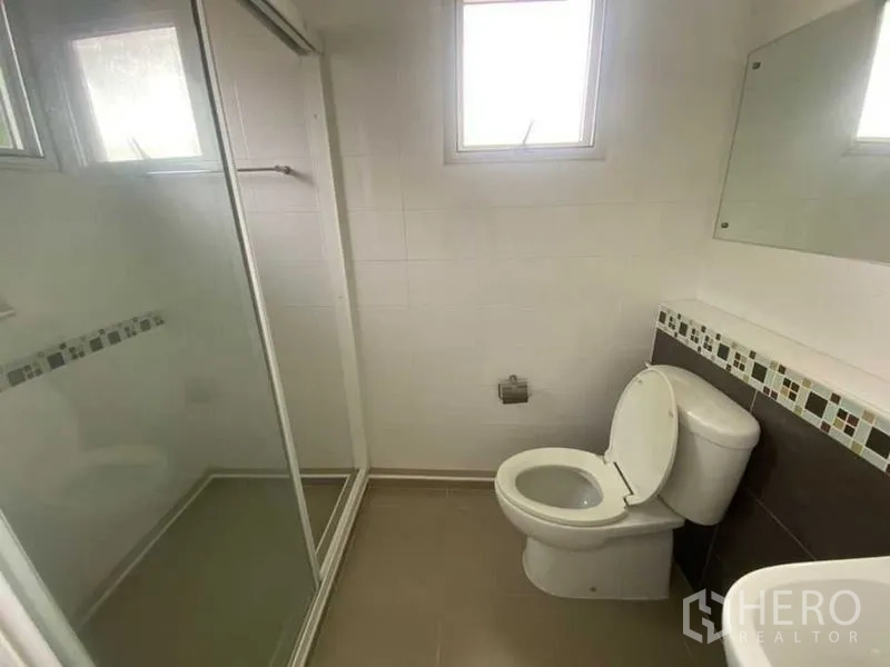 Detached House for rent - Clean bathroom with glass-enclosed shower, window and wall mirror.