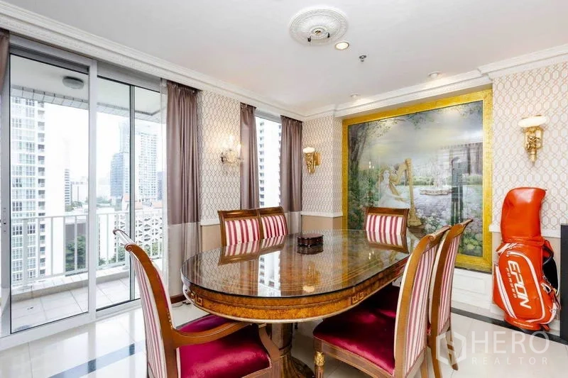 Condominium for rent or sale in Pathum Wan, Bangkok - Formal dining area with oval wood table, feature wall art, and balcony access.