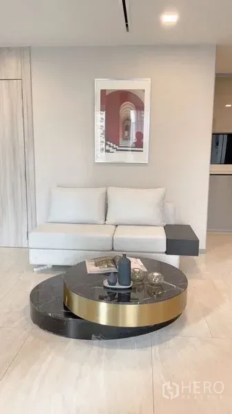 公寓 出租在Watthana, Bangkok - 舒适客厅一角，浅色沙发、圆形大理石茶几与装饰画。