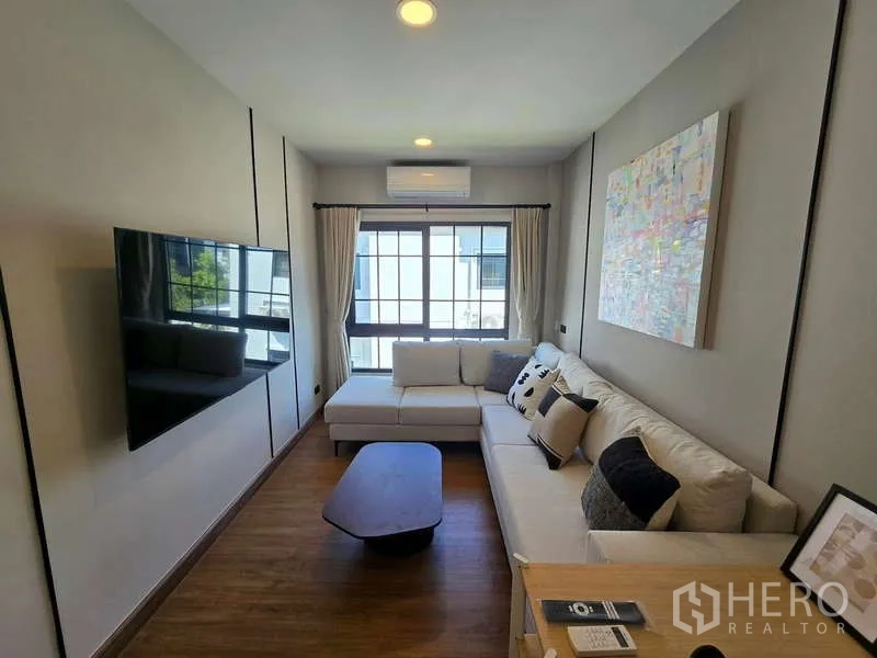 Detached House for rent in Bang Phli, Samut Prakan - Cozy family room with L-shaped sofa, wall-mounted TV and large window.