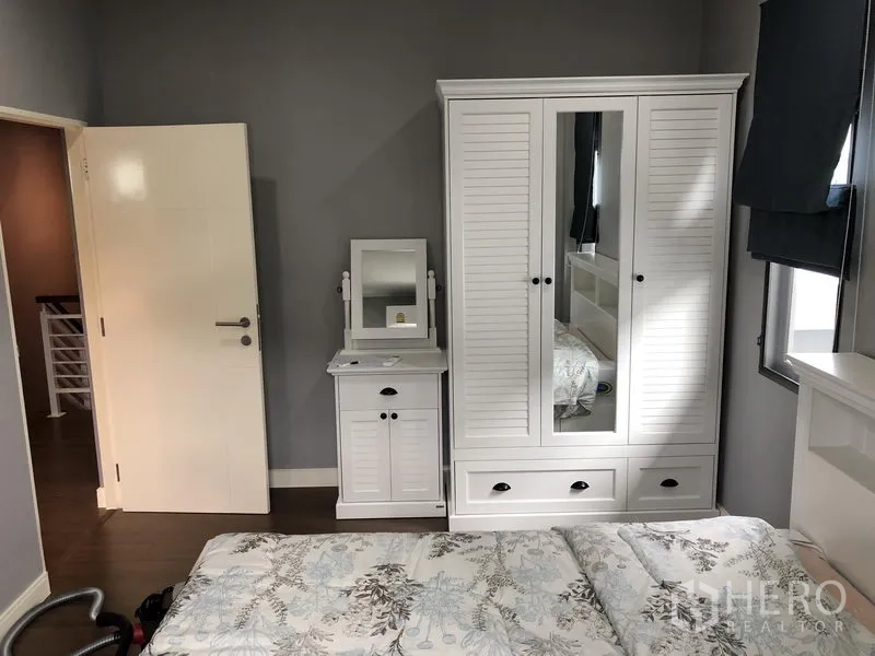 Detached House for rent in Bang Kapi, Bangkok - Cozy bedroom with white wardrobe and dressing table beside a window.