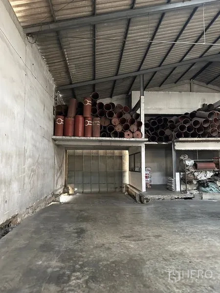 Warehouse for rent in Lat Krabang, Bangkok - Mezzanine platform storing large pipes beneath a steel roof inside the warehouse.