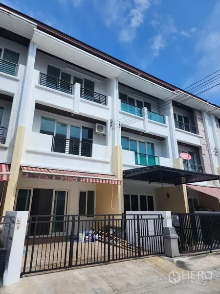 Townhouse for rent in Wang Thonglang, Bangkok - Exterior of a three-storey modern townhouse with balconies and gated carport.