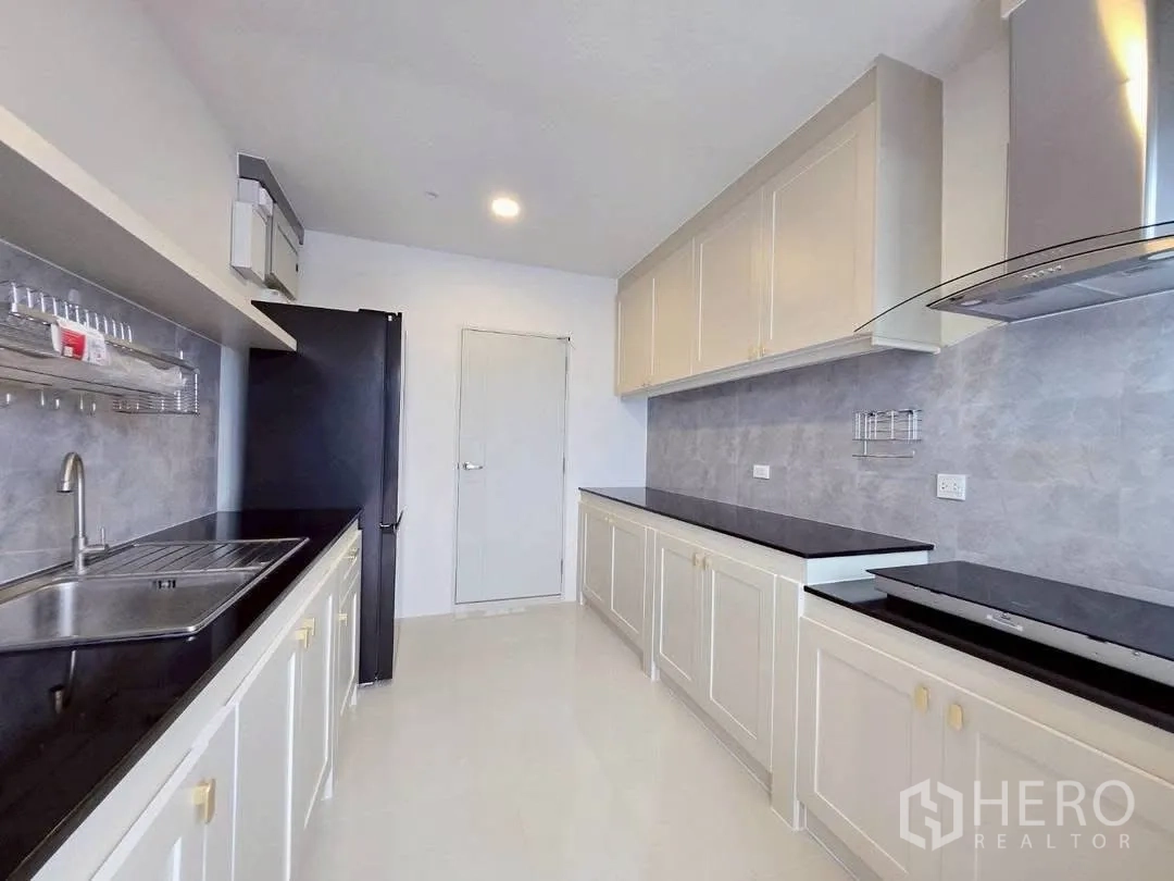 Detached House for rent in Bang Phli, Samut Prakan - Bright contemporary kitchen with long black countertops, white cabinetry, and a range hood.