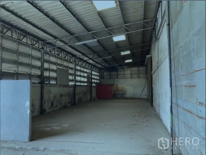 Factory for rent in Samut Prakan - Long warehouse bay with metal cladding, strip skylights and open production space on a concrete slab.