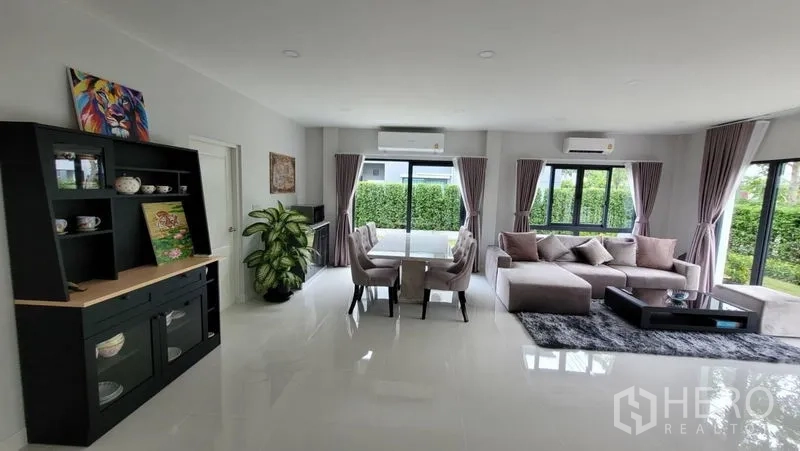 Detached House for rent in Don Mueang, Bangkok - Open-plan living and dining area with glossy floors and views to a private hedge-lined yard.