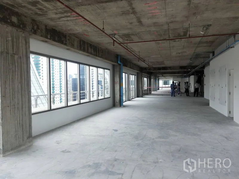 Office Space for rent in Watthana, Bangkok - Open-plan unfinished office with a long window line overlooking city buildings.