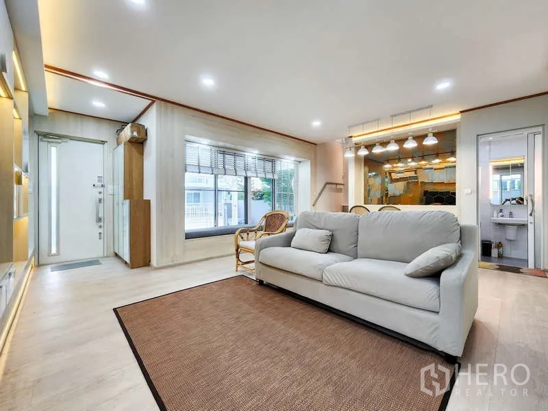 Detached House for rent or sale in Prawet, Bangkok - Spacious living room with bay window bench, neutral sofa and bright ceiling lights.
