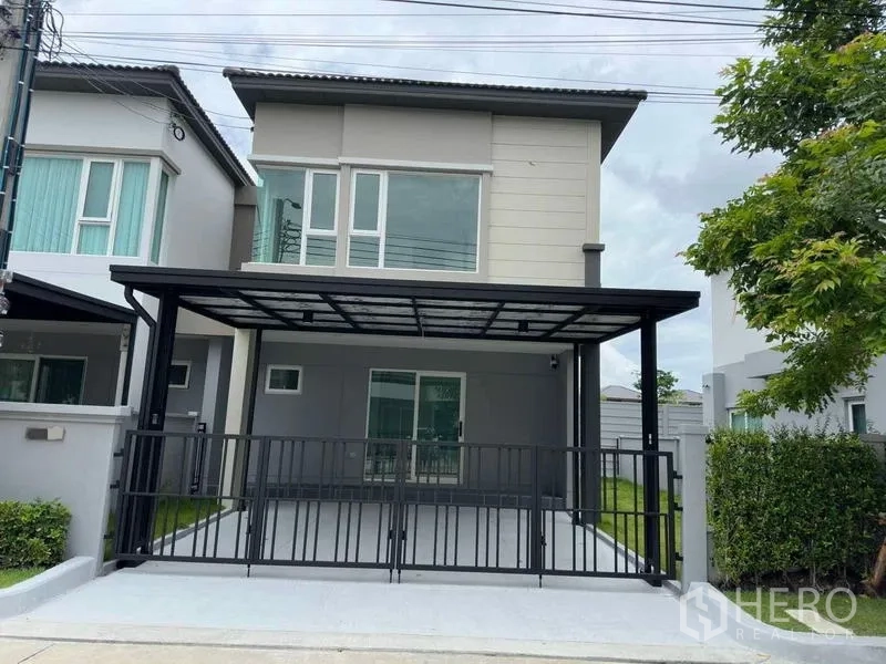 Detached House for rent in Bang Phli, Samut Prakan - Front elevation of detached house with gated driveway and metal awning.
