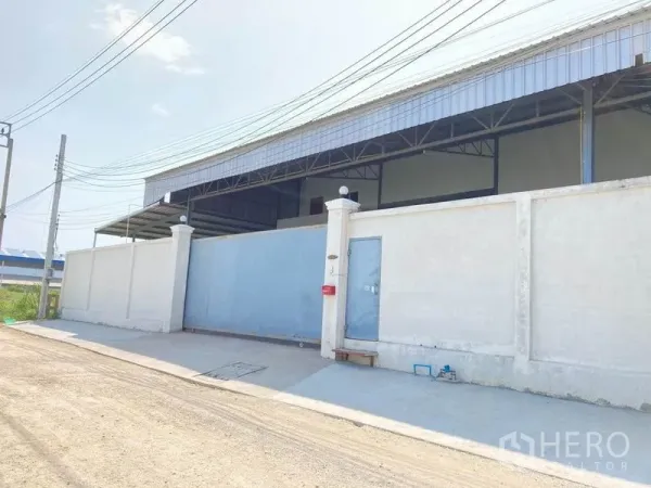 货栈 出租在Bang Phli, Samut Prakan - 仓库外立面，混凝土围墙与蓝色滑动金属门，位于邦普里。
