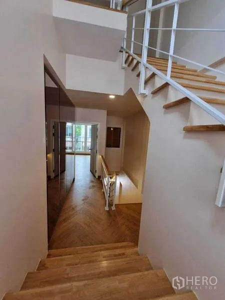 ทาวน์เฮาส์ ให้เช่าในWang Thonglang, Bangkok - มุมมองลงบันได ราวเหล็กสีขาว พื้นไม้สู่โถงนั่งเล่น