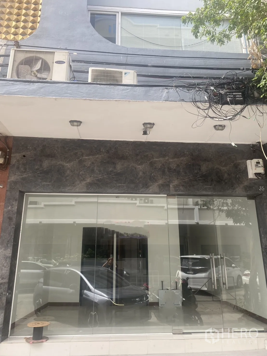 Shophouse for rent in Bang Rak, Bangkok - Street-level shophouse frontage with full-height glass and dark stone cladding.