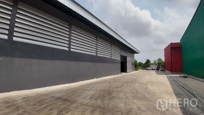 Warehouse for rent in Chachoengsao - Driveway beside the warehouse with neighboring buildings and open loading area.