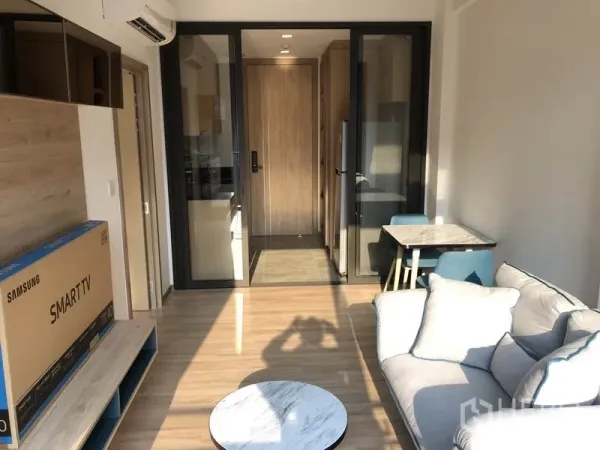 คอนโด ให้เช่าในWatthana, Bangkok - ห้องนั่งเล่นสว่างด้วยโซฟา ชั้นวางทีวี และประตูกระจกบานเลื่อนเชื่อมครัวและทางเข้าในคอนโดสมัยใหม่