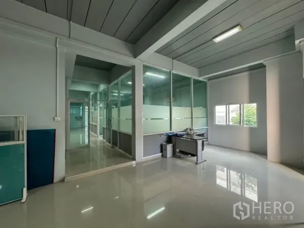 Warehouse for rent or sale in Chon Buri - Open-plan office area with frosted glass partitions, windows and a work desk.