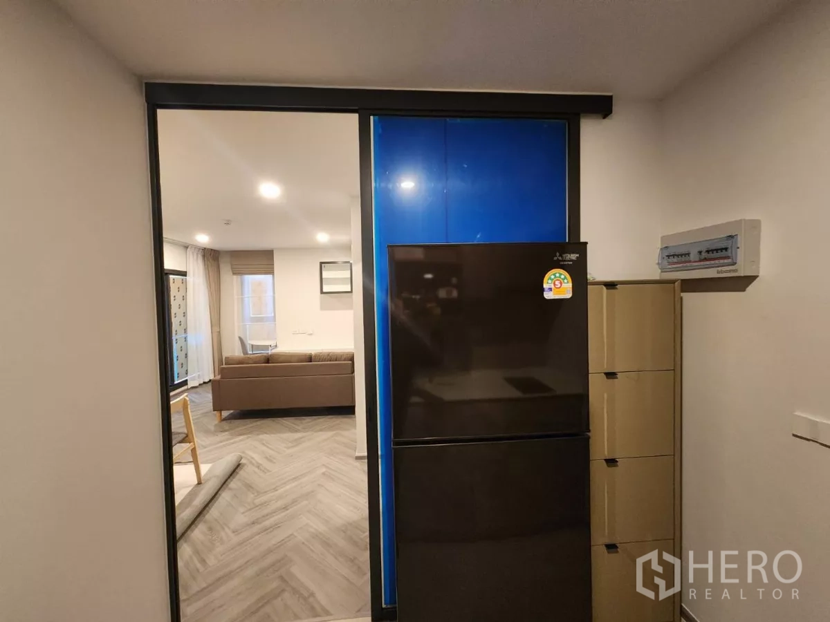 Townhouse for rent in Khlong Toei, Bangkok - Kitchen storage with double‑door refrigerator viewed through a sliding door.
