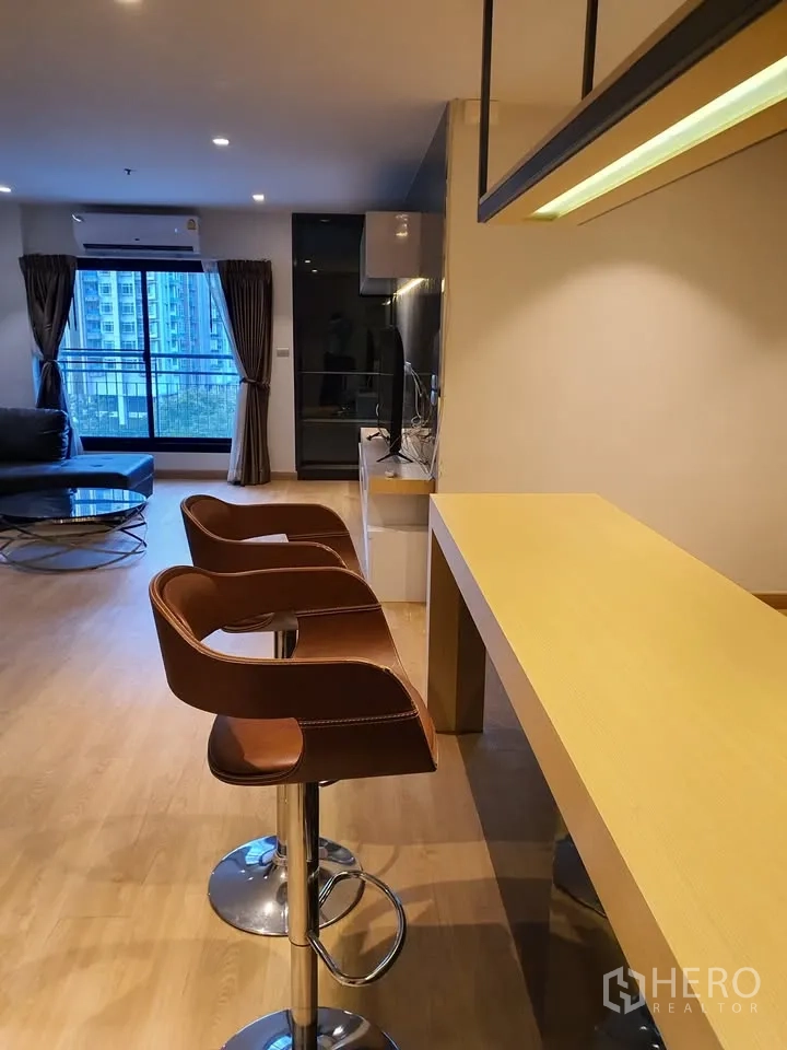 คอนโด for rent in Watthana, Bangkok - เคาน์เตอร์บาร์พร้อมสตูลหนังสองตัว ข้างพื้นที่นั่งเล่นและหน้าต่างบานใหญ่