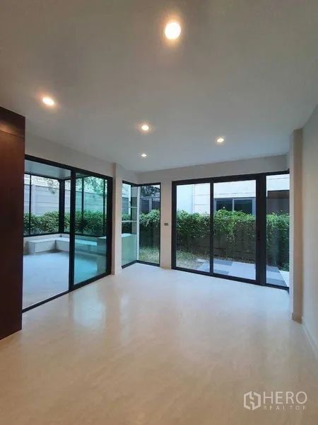 Detached House for sale in Prawet, Bangkok - Ground-floor living space with full-height glass doors to patio and greenery.
