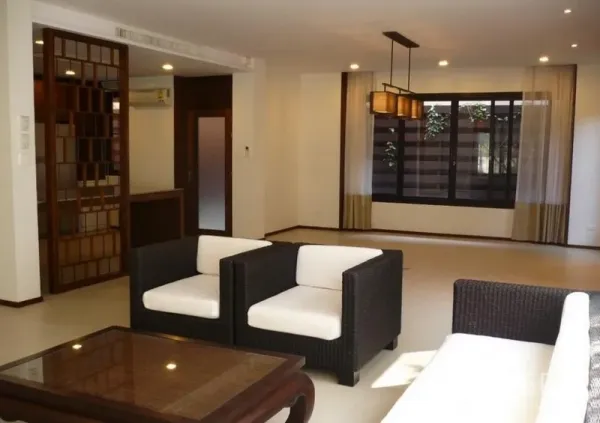Detached House for rent in Khlong Toei, Bangkok - Spacious open-plan living room with rattan sofa set, large window and warm lighting in a Bangkok detached house.
