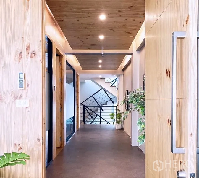 办公空间 出租在Bang Rak, Bangkok - 走廊配木质天花与大门，绿植点缀，通向楼梯间