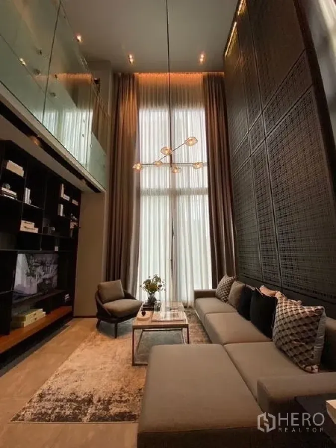 บ้าน ขายในPhaya Thai, Bangkok - มุมมองอีกด้านของห้องนั่งเล่นเพดานสูงโปร่ง โซฟาตัวแอลและผนังดีไซน์