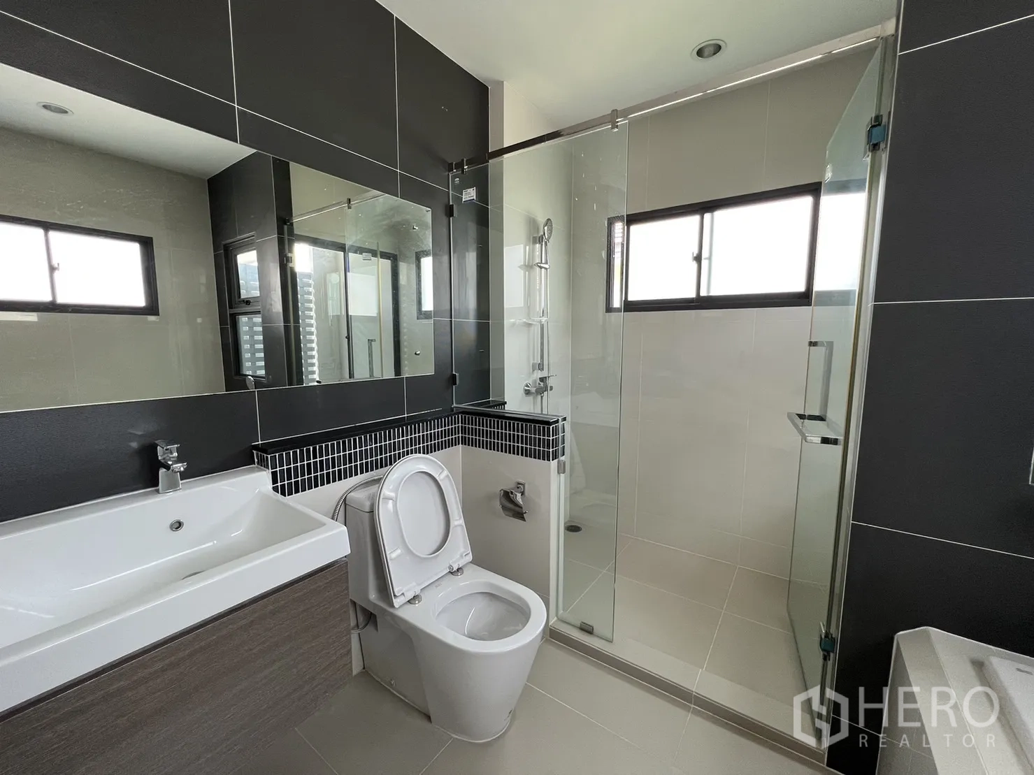 Detached House for sale in Suan Luang, Bangkok - Tiled bathroom with glass shower, large mirror and modern fittings.