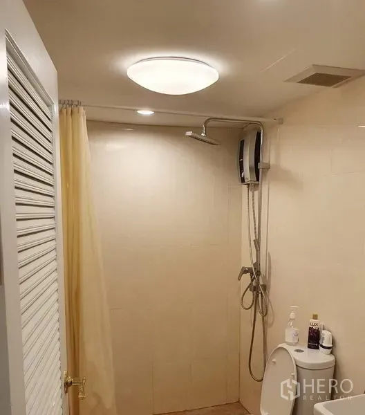 Condominium for rent in Watthana, Bangkok - Tiled bathroom with walk-in shower, water heater, shower curtain, and toilet.