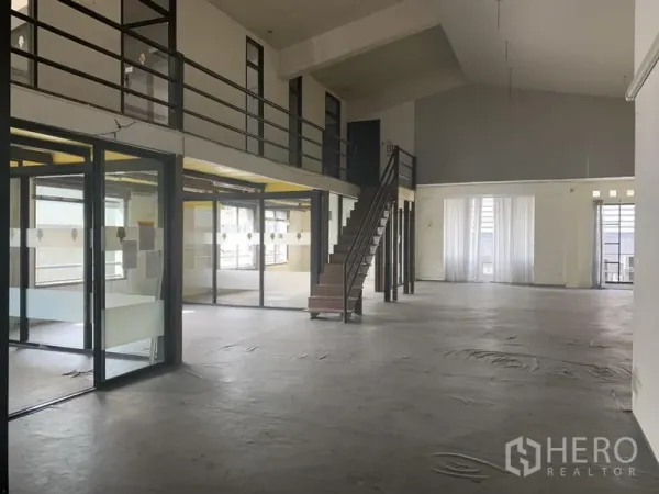 零售空间 出租在Khlong Toei, Bangkok - 零售空间一侧为玻璃办公室，夹层走道与中央楼梯，穹顶式高顶。