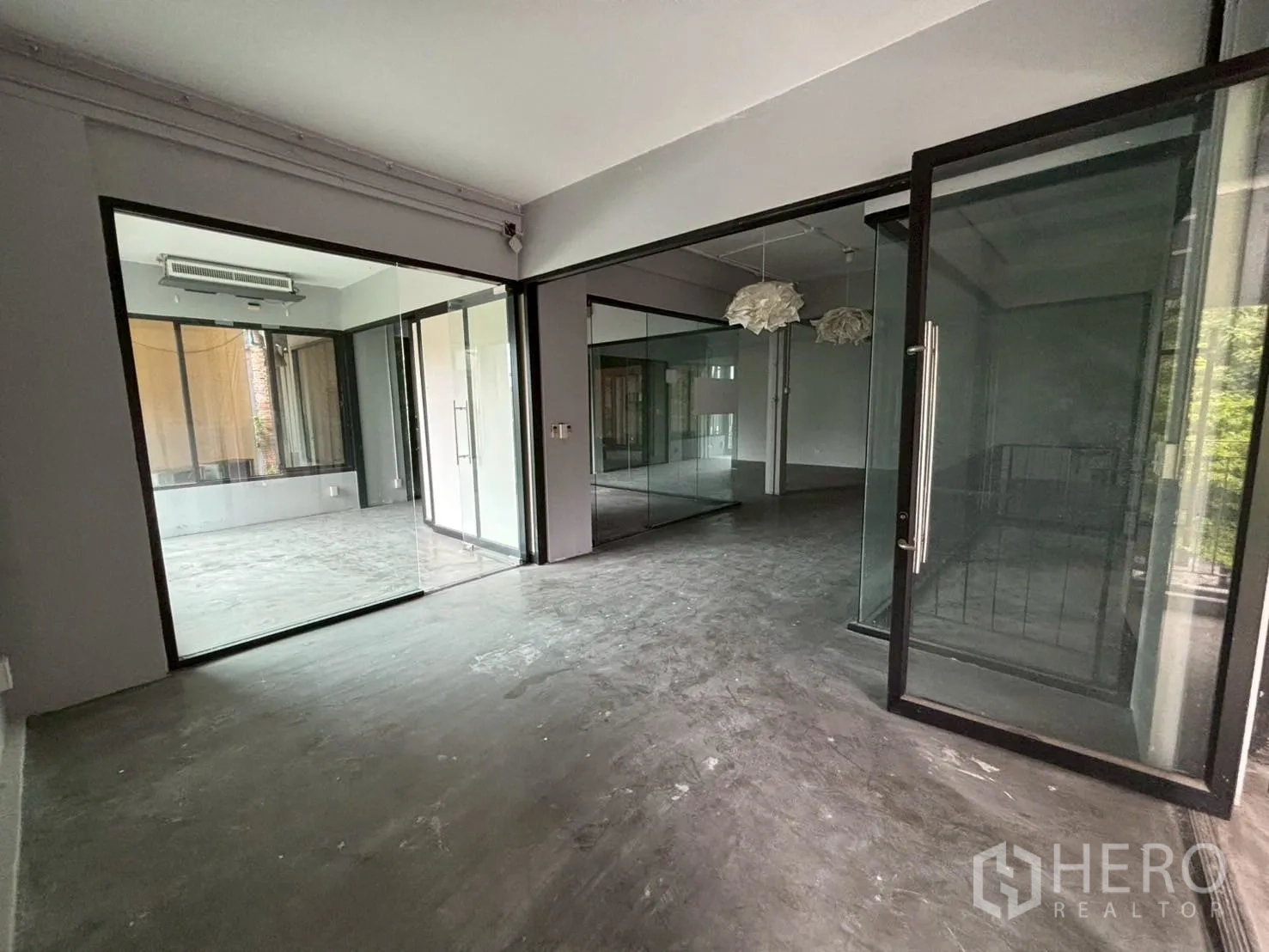 สำนักงาน ให้เช่า - โถงสำนักงานสว่างไสว พร้อมห้องประชุมกระจกหลายห้องและโคมไฟแขวน.