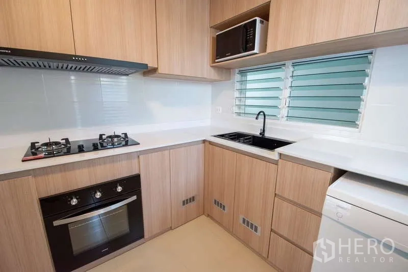 Detached House for rent in Bang Phli, Samut Prakan - Close-up of kitchen cooking zone with stove, sink and microwave.