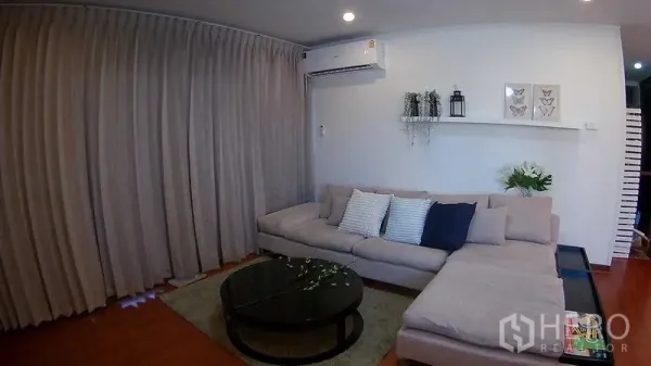 คอนโด ให้เช่าหรือขายในDin Daeng, Bangkok - ห้องนั่งเล่นคอนโดในดินแดง กรุงเทพฯ พร้อมโซฟาเข้ามุม ชั้นวางของ แอร์ และพื้นไม้โทนอบอุ่น.