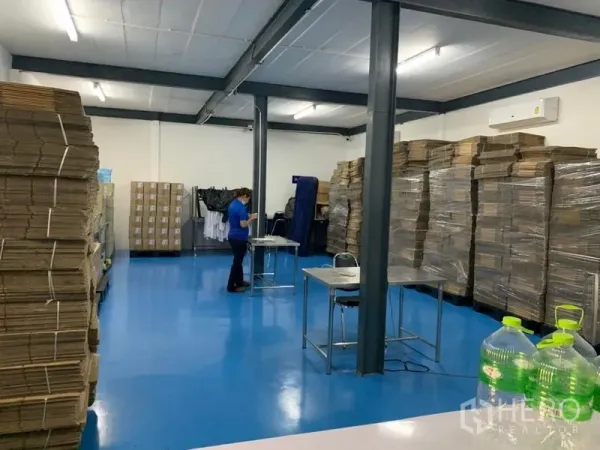 คลังสินค้า ให้เช่าในBang Kapi, Bangkok - พื้นที่ทำงานในโกดังพื้นอีพ็อกซี่สีน้ำเงิน เสาเหล็ก กล่องสินค้าวางซ้อน และแอร์ผนัง.