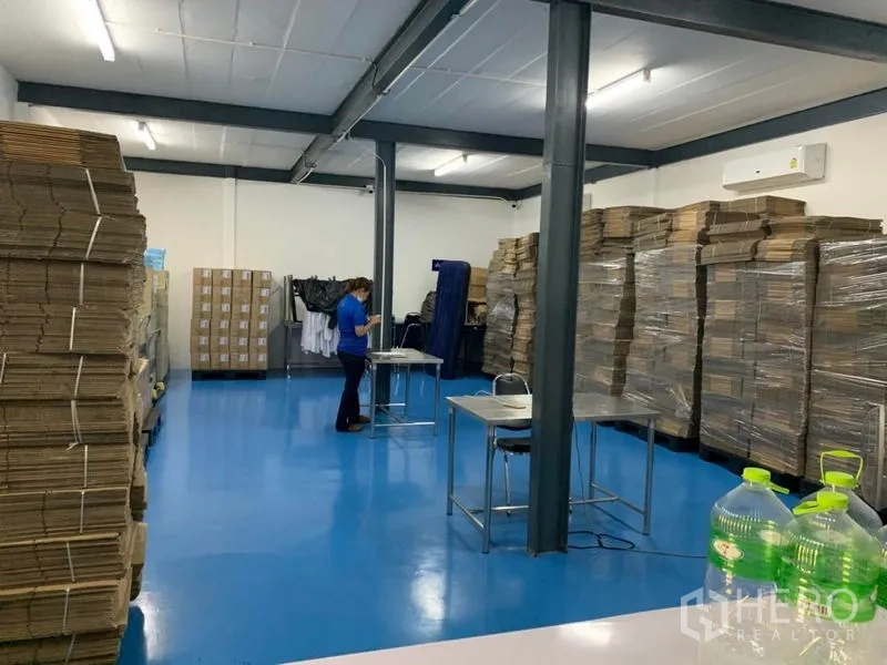 คลังสินค้า ให้เช่าในBang Kapi, Bangkok - พื้นที่ทำงานในโกดังพื้นอีพ็อกซี่สีน้ำเงิน เสาเหล็ก กล่องสินค้าวางซ้อน และแอร์ผนัง.