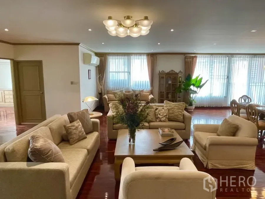 Condominium for rent or sale in Watthana, Bangkok - Bright lounge with multiple seating sets, ceiling lights, and sheer curtains along wide windows.
