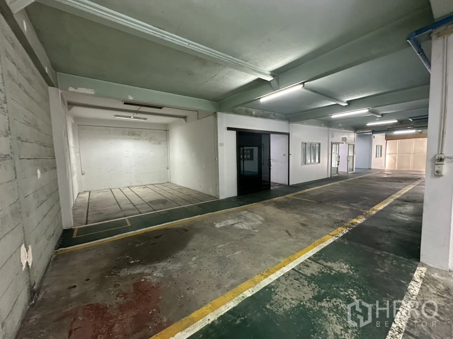 Warehouse for rent in Bang Na, Bangkok - Corridor view with recessed work area and dark glass entry door.