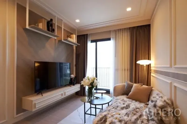 คอนโด ขายในRatchathewi, Bangkok - ห้องนั่งเล่นพร้อมผนังทีวีและชั้นลอย โซฟานั่งสบาย ประตูกระจกออกระเบียง