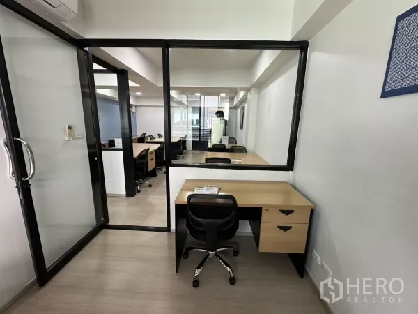 Office Space for rent in Watthana, Bangkok - Small workstation beside a glass door and interior window looking into the main workspace.