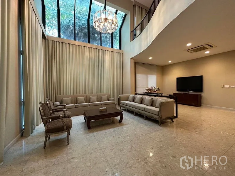 Detached House for rent or sale in Khan Na Yao, Bangkok - Double-height living room with grand chandelier and tall curtained windows.