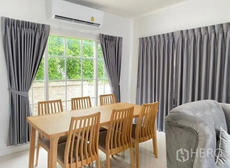 Detached House for rent or sale - Dining room with wooden six-seat table beside large windows, air-conditioning and grey drapes.