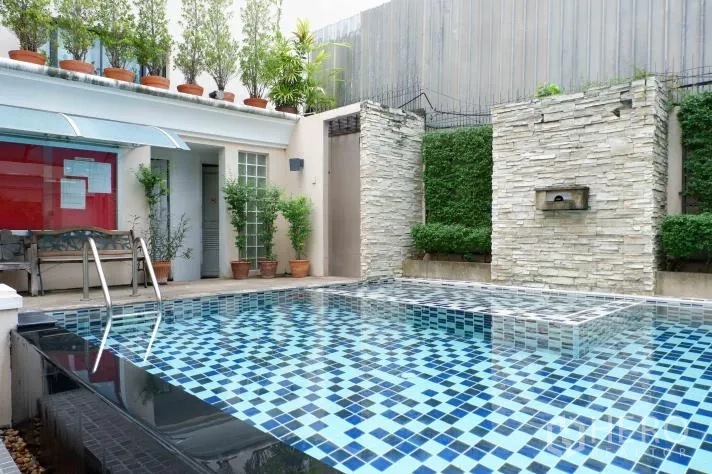 ทาวน์เฮาส์ ให้เช่าในKhlong Toei, Bangkok - สระว่ายน้ำกลางแจ้งปูกระเบื้องโมเสกสีน้ำเงิน ผนังหิน และต้นไม้ร่มรื่น