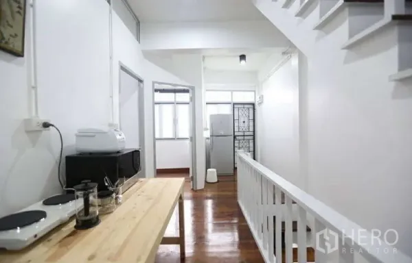 สำนักงานที่บ้าน ให้เช่าในKhlong Toei, Bangkok - โถงทางเดินสว่างพร้อมโต๊ะแพนทรี ราวบันไดสีขาว และพื้นไม้ทางไปยังหลายห้อง