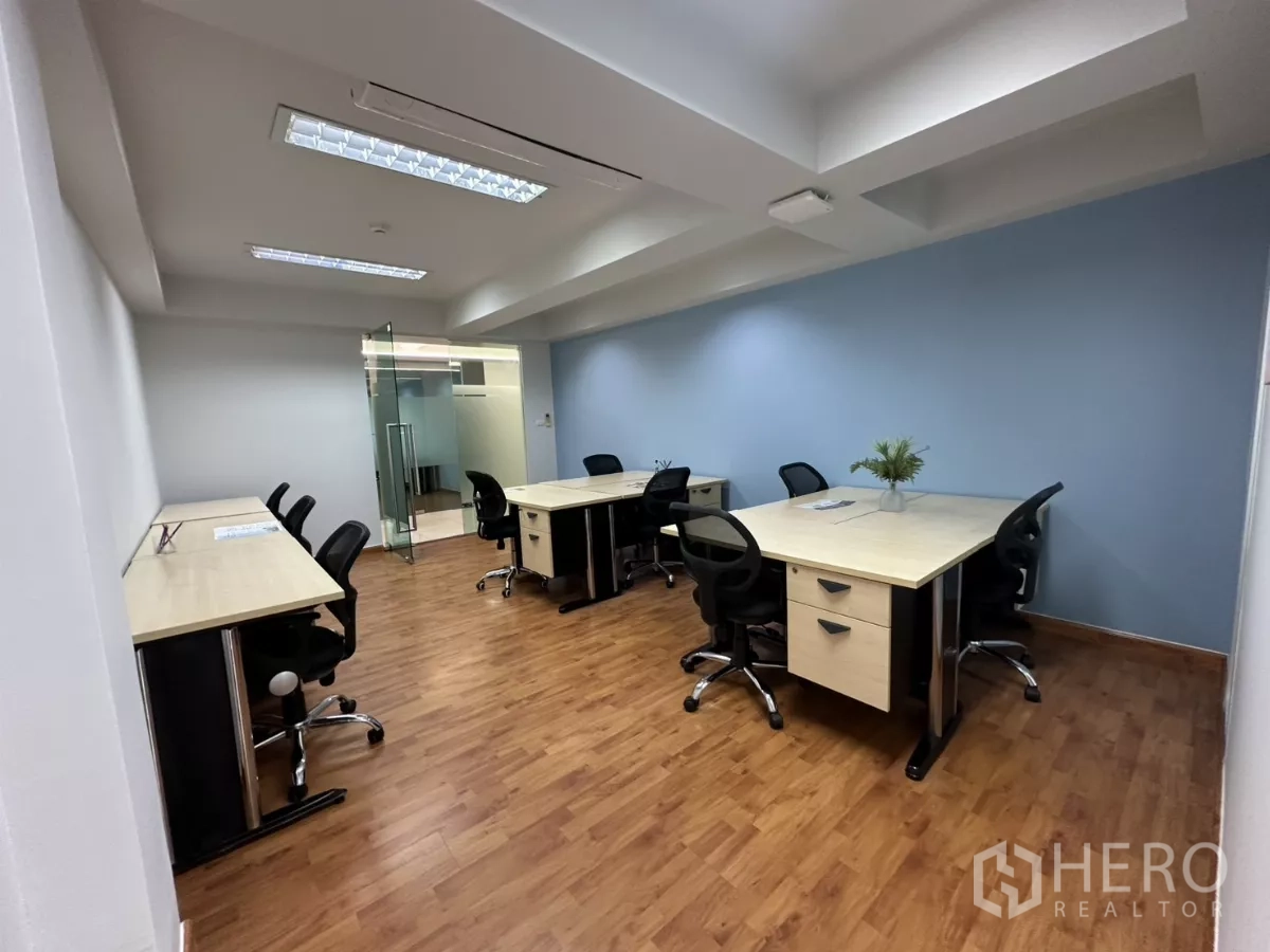 Office Space for rent in Watthana, Bangkok - Collaborative workspace with bench desks, rolling chairs and a glass meeting-room door.