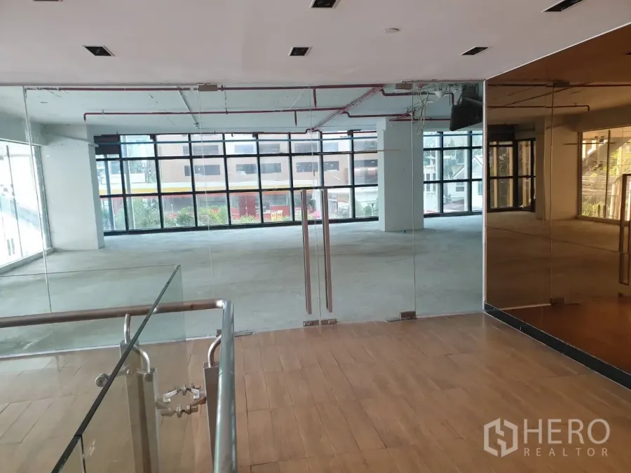 零售空间 出租在Watthana, Bangkok - 玻璃双开门入口，镜面墙与木地板，通向采光充足的零售区。