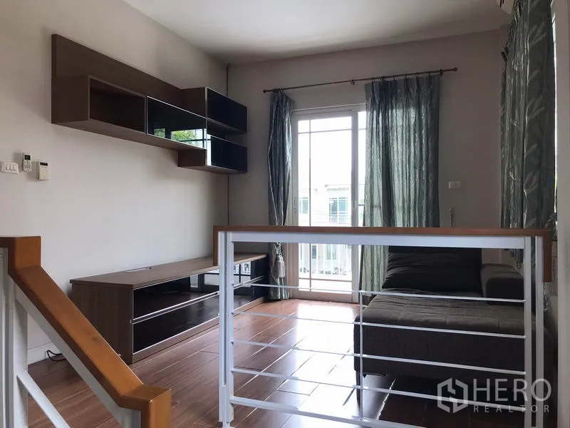 Detached House for rent in Khlong Sam Wa, Bangkok - Upstairs family lounge with sofa, wall shelves and sliding door to balcony.